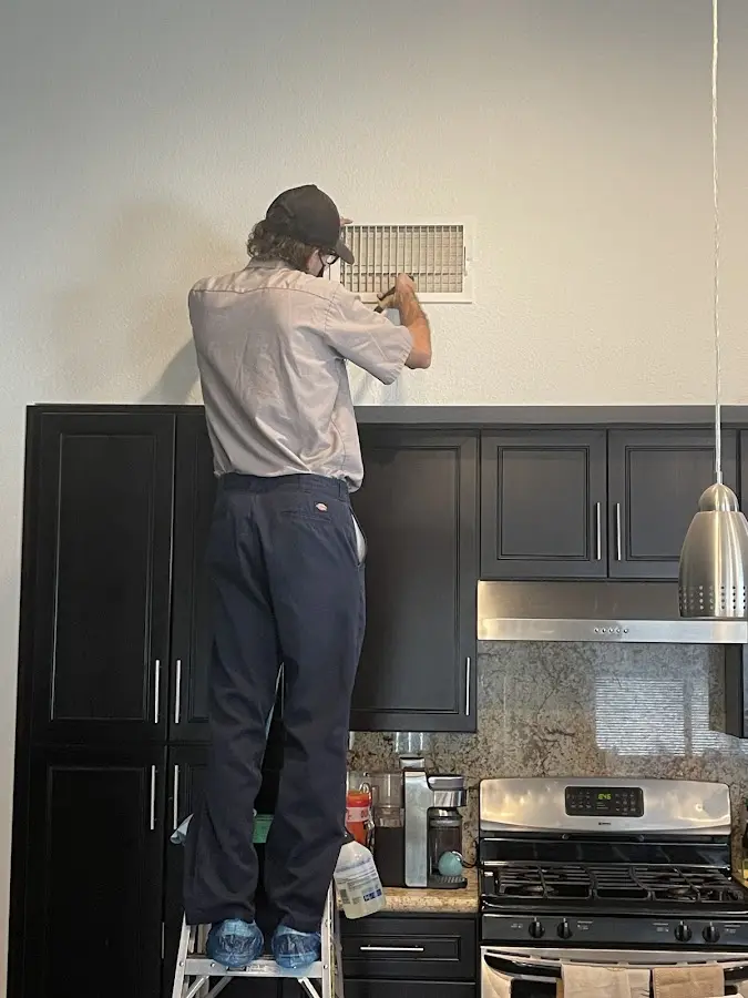 Technician inspecting an air vent during HVAC service in Lawrence